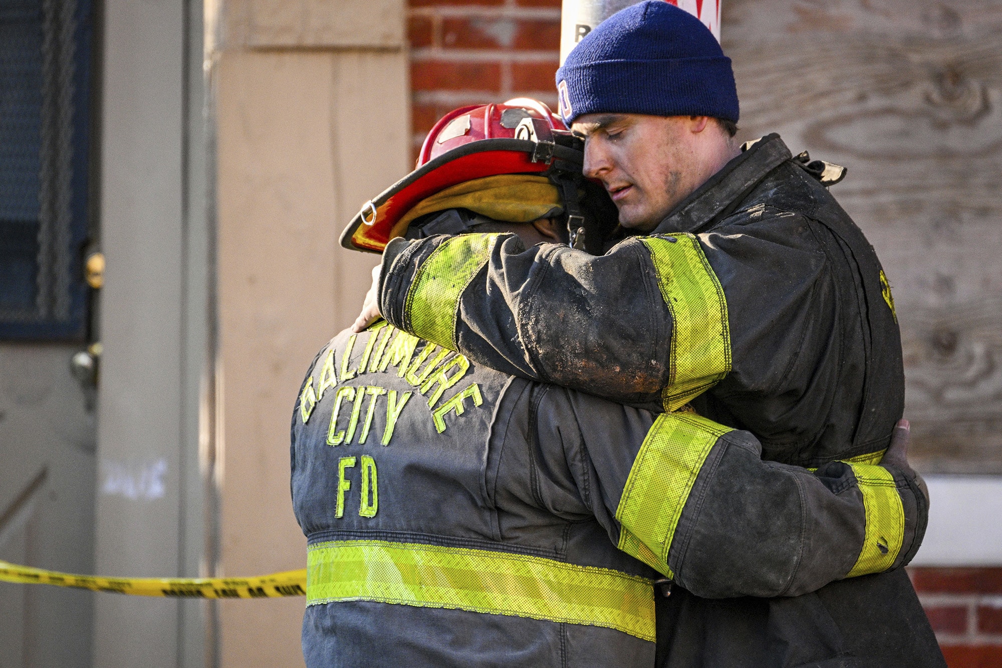 Dos Bomberos de Baltimore abrazan despues de fuego que mato 3 otro bomberos